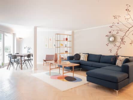 Heller Wohn- und Essbereich mit Blick auf den Terrassenausgang, Esstisch mit schwarzen Stühlen und Design-Dekoration im Vordergrund.