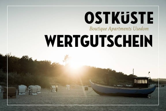 Ein blaues Fischerboot und weiße Strandkörbe am Usedomer Sandstrand im warmen Gegenlicht der Sonne, darüber der Schriftzug OSTKÜSTE Wertgutschein.